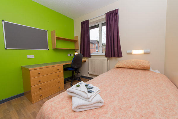 A bedroom inside Ƶ of Worcester accommodation. There is a single bed, a large pin board, desk, chest of drawers and a window in the room.